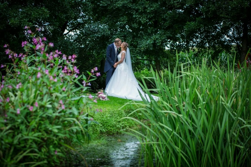 A wedding couple kissing by the pond at Haselbury Mill Wedding Venue, taken by Somerset Photographer Victoria Welton